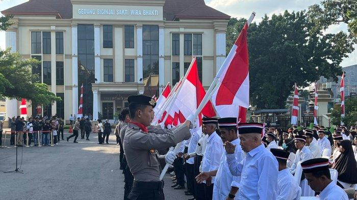 Warga memberi hormat ke Bendera Merah Putih saat pelepasan baiat Negara Islam Indonesia (NII), di lapangan Mapolda Jambi, Kamis (25/7).