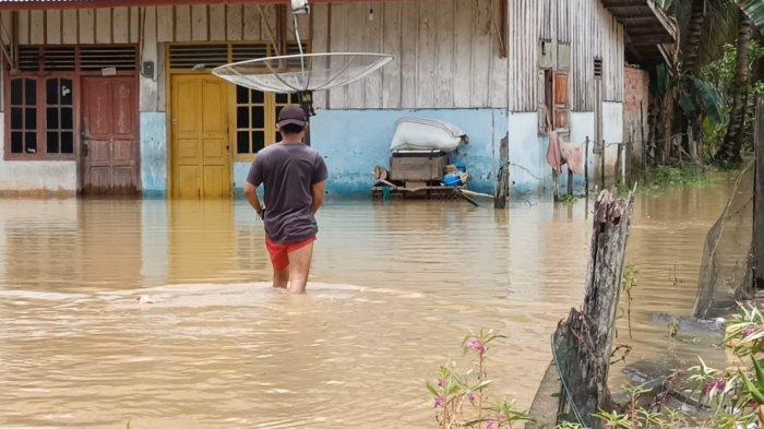 Warga melintas di jalan yang terendam banjir di Kecamatan Sarolangun. Setidaknya lima kelurahan dalam Kecamatan Sarolangun terendam banjir.
