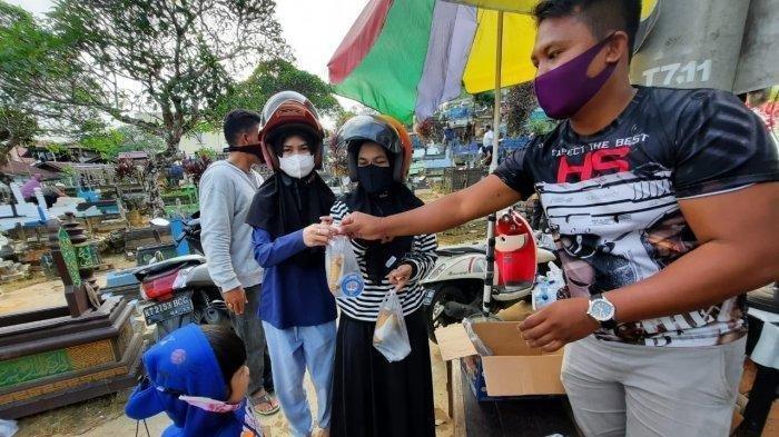 Bripka Joko Hadi Aprianto (Kanan) memberikan takjil kepada peziarah makam muslimin Peng Ah Kelurahan Karang Anyar kecamatan Sungai Kunjang, Rabu (12/5/2021).