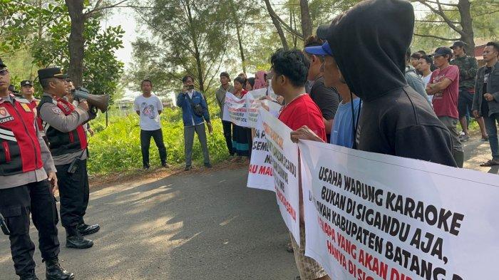 Puluhan pengusaha kafe dan karaoke di kawasan wisata Pantai Sigandu, Kabupaten Batang, Jawa Tengah, menggelar aksi protes dramatis dengan menghadang laju tim gabungan dari Satpol PP, TNI, dan Polri, Rabu (9/7/2025). Aksi ini sebagai bentuk penolakan terhadap rencana pembongkaran paksa bangunan usaha mereka yang dinilai tidak berizin.