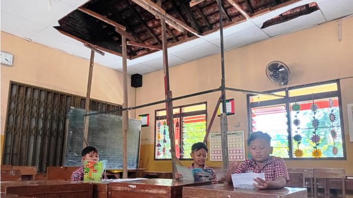 Beberapa siswa belajar di ruang kelas 2 SDN 5 Ngembalrejo Kudus yang atapnya ambrol, Kamis (17/7/2025). Kerusakan atap terebut sudah berlangsung lebih dari setahun dan belum mendapatkan perhatian dari Pemkab Kudus.