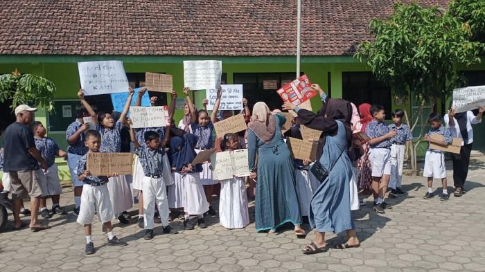 TOLAK REGROUPING - Aksi para siswa dan wali murid SDN Tayu Kulon 01, Kecamatan Tayu, Pati, yang menolak regrouping atau penggabungan dengan SDN Tayu Kulon 02, Kamis (17/7/2025). Sudah empat hari mereka tetap datang ke SDN Tayu Kulon 01 sekalipun tidak ada aktivitas belajar-mengajar lagi karena secara administratif sudah dilebur ke SDN 02. 