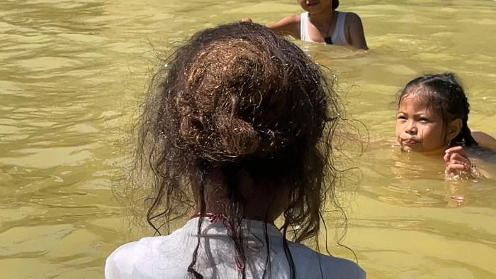 RUWAT RAMBUT GIMBAL - Sepuluh anak perempuan menjalani prosesi Jamasan mencuci dan mensucikan anak secara lahir batin, di kolam air hangat Taman Rekreasi Kalianget Wonosobo, Senin (21/7/2025). Prosesi ini dilakukan sebelum puncak prosesi dengan pencukuran rambut gimbal pada 24 Juli mendatang.