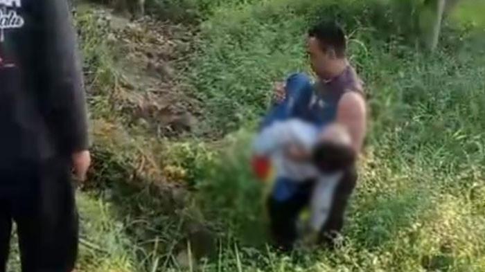 EVAKUASI KORBAN KECELAKAAN: Kanit Provost Polsek Galis, Aipda Afik Iswanto, mengangkat tubuh pemotor Honda Vario dari tegalan setelah kendaraannya bertabrakan depan dengan Toyota Innova di Jalan Raya Desa Separah, Kecamatan Galis pada Rabu (23/7/2025) sekitar pukul 06.30 WIB. (TRIBUN JATIM/ISTIMEWA)