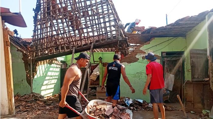 BERSIHKAN PUING - Warga bergotong-royong membersihkan puing-puing reruntuhan rumah yang mengalami roboh, Kamis (31/7/2025). Rumah joglo berusia 60 tahun yang ditinggali oleh Kuswarin ini merupakan warisan kakek dan nenek dua generasi.