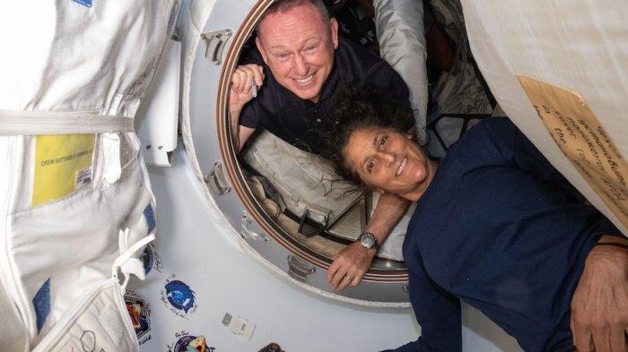 Astronot Uji Penerbangan Kru Boeing NASA (dari atas) Butch Wilmore dan Suni Williams berpose di dalam ruang depan antara port depan pada modul Harmony Stasiun Luar Angkasa Internasional dan pesawat ruang angkasa Boeing Starliner.