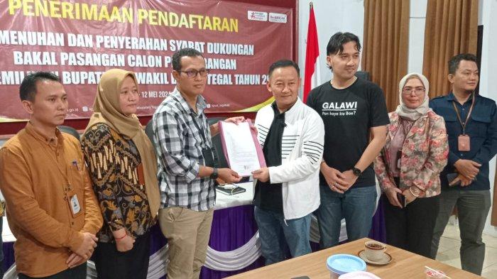 Bakal Calon Bupati Tegal H Muhammad Mu'min (pakai jaket putih), didampingi Bakal Calon Wakil Bupati Tegal Bima Eka Sakti (kaos hitam), simbolis menyerahkan formulir pendaftaran jalur perseorangan atau independen kepada Ketua Komisi Pemilihan Umum (KPU) Kabupaten Tegal Himawan Tri Pratiwi. Berlokasi di Kantor KPU Kabupaten Tegal, Minggu (12/5/2024).