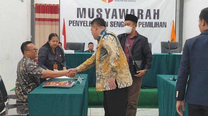 Ketua KPU Kendal, Khasanudin berjabat tangan dengan kuasa hukum Dico - Ali, Fajar Saka (duduk) seusai sidang gugatan di Gedung Sentra Gakkumdu Bawaslu Kendal, Sabtu (14/9/2024). 
 