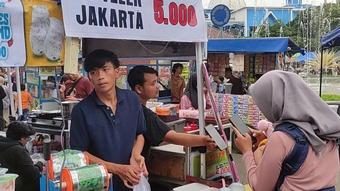 LAYANI PELANGGAN- Amir Abdillah melayani pelanggan yang membeli ciloknya di Desa Dukuhwaluh Kecamatan Kembaran, Banyumas, Kamis (27/3/2025). Pedagang ini menggunakan QRIS untuk transaksi digital. 