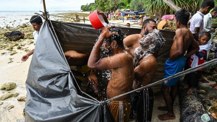 Para pengungsi Rohingya membersihkan diri di belakang terpal di pantai Pulau Sabang, provinsi Aceh, Indonesia pada 3 Desember 2023. Lebih dari 100 pengungsi Rohingya, termasuk perempuan dan anak-anak, mendarat di provinsi paling barat Indonesia pada 2 Desember, kata pejabat, tetapi warga setempat mengancam akan mendorong mereka kembali ke laut.
CHAIDEER MAHYUDDIN / AFP