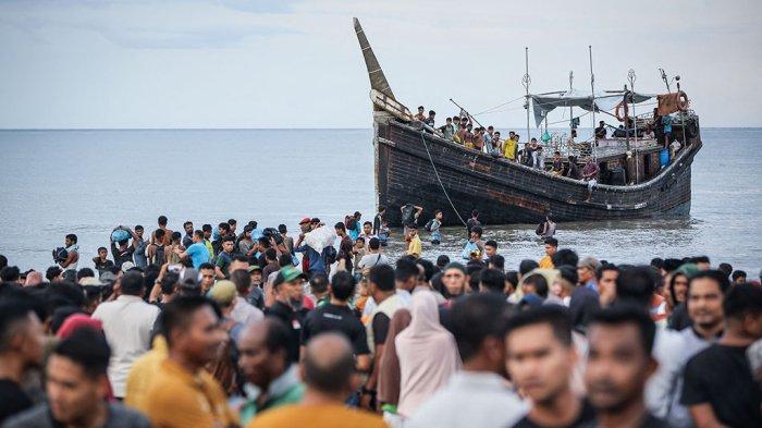 Pengungsi Rohingya yang baru tiba kembali ke perahu setelah masyarakat setempat memutuskan untuk mengizinkan mereka sementara mendarat untuk mendapatkan air dan makanan di Ulee Madon, provinsi Aceh, Indonesia, pada 16 November 2023. Sekitar 250 pengungsi Rohingya mencapai Indonesia bagian barat dengan perahu kayu yang penuh sesak pada 16 November 2023, sehingga jumlah pengungsi yang dilaporkan oleh pejabat setempat tiba pada minggu ini menjadi hampir 600 orang. (Photo by amanda jufrian / AFP)