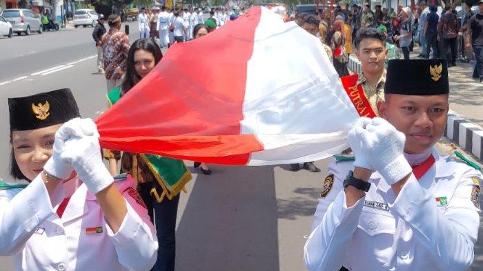 Peserta membentangkan bendera merah putih sepanjang 1.000 meter dalam rangka memperingati Hari Sumpah Pemuda dan HUT Karanganyar ke-107 di Jalan Lawu Kabupaten Karanganyar, Minggu (27/10/2024) siang.