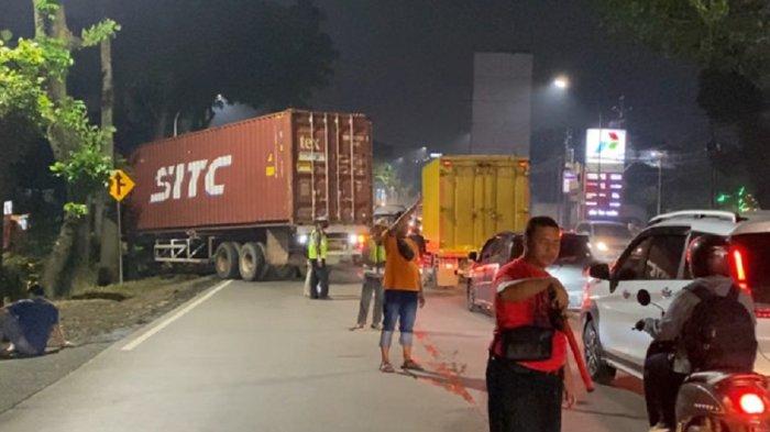 ATUR LALU LINTAS - Polisi dan relawan Bankom mengatur lalu lintas yang padat akibat penyempitan jalan di Jalan Perintis Kemerdekaan, Banyumanik, Kota Semarang, Jumat (25/4/2025) malam. Penyempitan terjadi karena adanya truk kontainer yang mengalami kecelakaan hingga posisinya menutup separuh jalur.