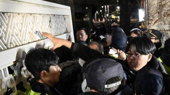 Polisi menahan massa yang memaksa masuk gedung Majelis Nasional di Seoul, Korea Selatan, Selasa (3/12/2024), setelah Presiden Yoon Suk Yeol mengumumkan darurat militer. (AFP/JUNG YEON-JE)