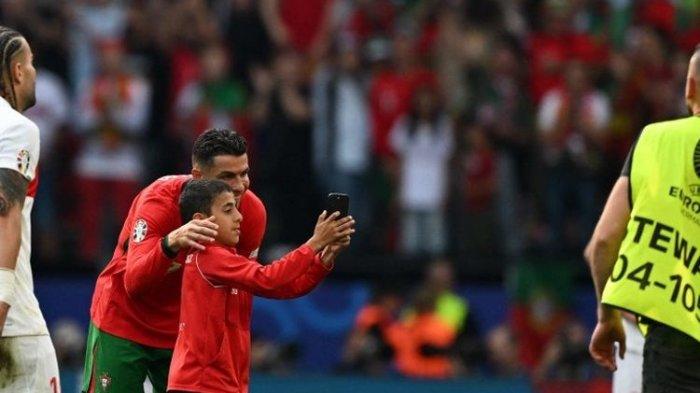 Penyerang timnas Portugal Cristiano Ronaldo berpose untuk selfie dengan penyusup fans muda di lapangan pada pertandingan Grup F Euro 2024 antara Turkiye vs Portugal di BVB Stadion di Dortmund pada 22 Juni 2024.