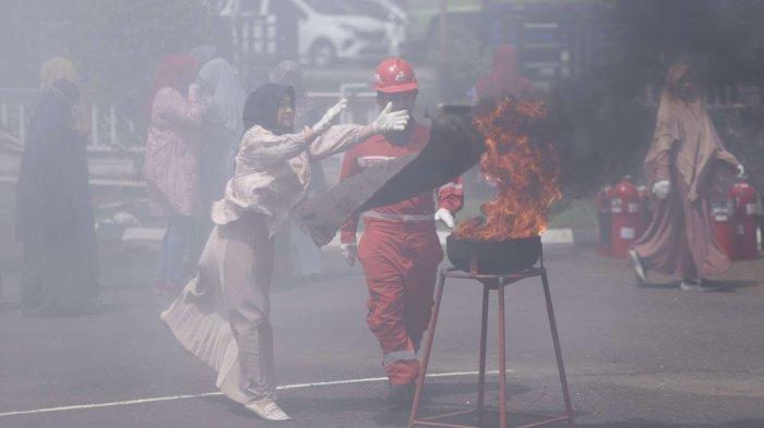 Salah satu peserta juga praktik langsung pemadaman api saat sosialisasi bahaya kebakaran bagi keluarga pekerja di gedung Patra Graha, Jumat (23/2/2024)