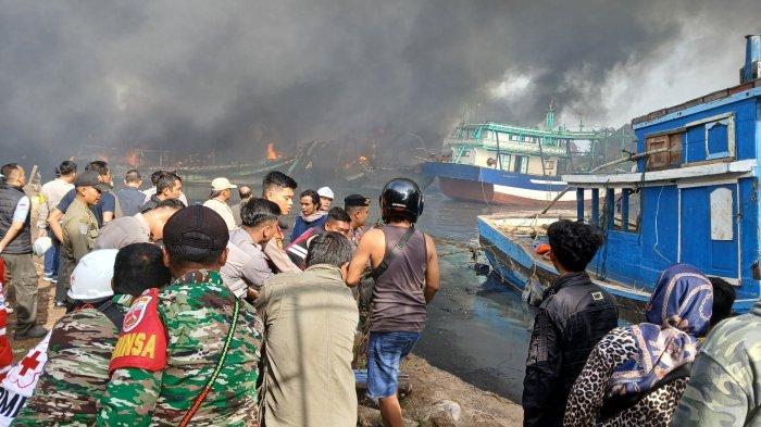 Warga dan aparat TNI Polri berusaha melokalisir kapal utuh agar tidak terdampak kapal terbakar di area Dok dan Galangan Kapal PT Pantai Mulia Semesta Tegal, Jumat (27/12/2024).