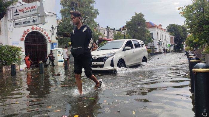 Warga menerabas banjir di kawasan Kota Lama Semarang, Kamis (14/3/2024)