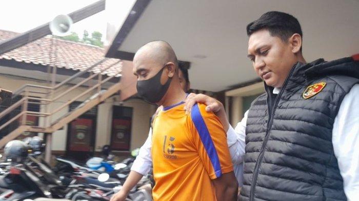 SP (45), berbaju jingga, guru yang melakukan perbuatan asusila terhadap sejumlah murid SD di Karawang, Jawa Barat, usai konferensi pers di Mapolres Karawang, Senin (20/11/2023).