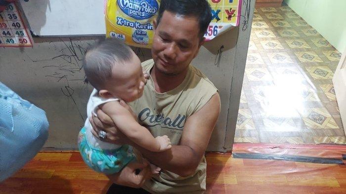 Algifari, bayi 8 bulan digendong oleh Herman, sang ayah.