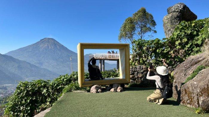 Wisatawan sedang menikmati keindahan panorama yang disuguhkan di wisata Pintu Langit Wonosobo dengan layar belakang gunung.