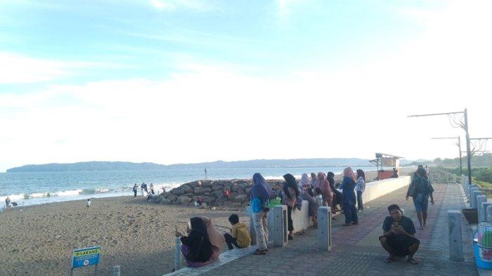 Sejumlah wisatawan saat menikmati suasana liburan di Pantai Kemiren, Cilacap di momen libur Hari Raya Waisak, Senin (12/5/2025) sore. Beberapa wisatawan penasaran dengan desain Pantai Kemiren yang menyerupai Pantai Ancol, Jakarta.