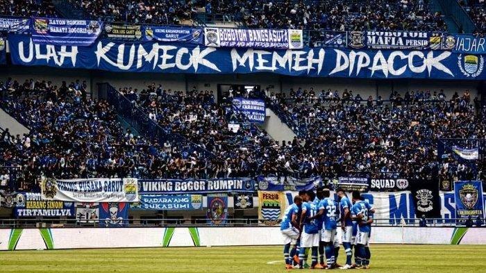 Para pemain Persib Bandung saat tengah berdiskusi di tengah lapangan, tampak para Bobotoh memberikan dukungan di tribun penonton.