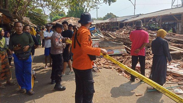 Polisi saat memasang garis police line di lokasi pasar darurat yang roboh.