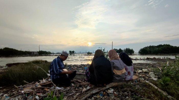 Peziarah saat berdoa di pesisir Semarang menghadap ke arah Tempat Pemakaman Umum (TPU) Tambakrejo, Tanjungmas, Kota Semarang, yang kini sudah direndam lautan, Jumat (1/4/2022).