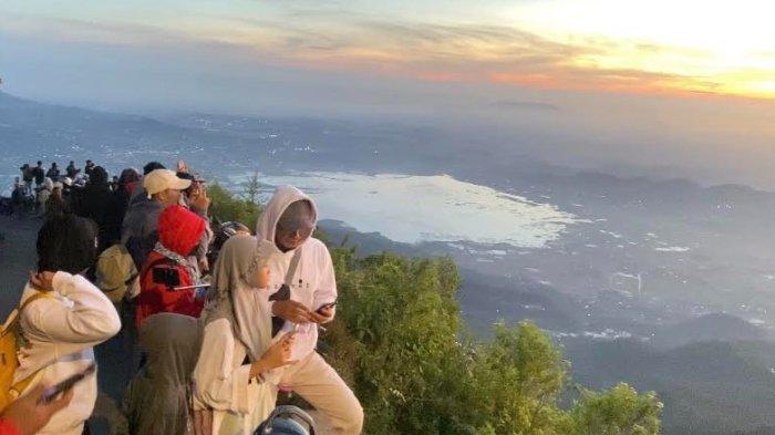 SERASA DI ATAS AWAN - Wisatawan berjejer di tepi jalan menikmati pemandangan alam seperti pegunungan, matahari terbit dan awan dari puncak Gunung Telomoyo, Desa Sepakung, Kecamatan Banyubiru, Kabupaten Semarang, Minggu (2/7/2023) pagi. Puncak gunung tersebut bisa diakses menggunakan kendaraan bermotor.