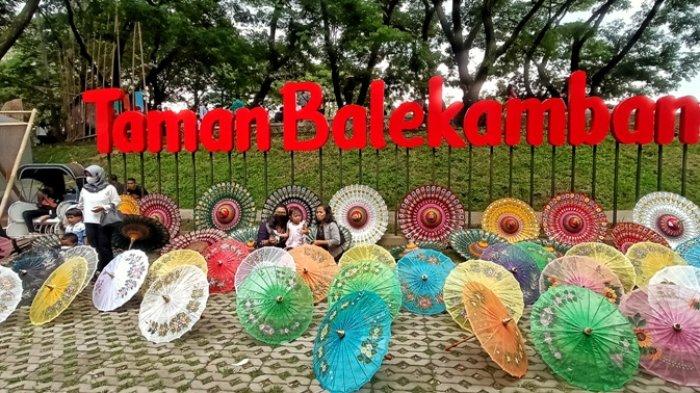 Para pengunjung saat berfoto di antara payung dengan latar bertuliskan Taman Balekambang, Minggu (5/12/2021).