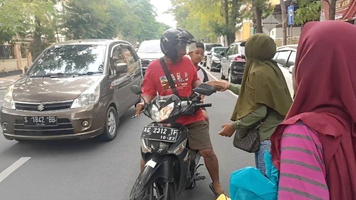 Keluarga Suyatno saat membagi kotak nasi ayam geprek kepada pengendara yang melintas di Lapas Kelas IIA Bojonegoro, Rabu (7/2/2024) sore.