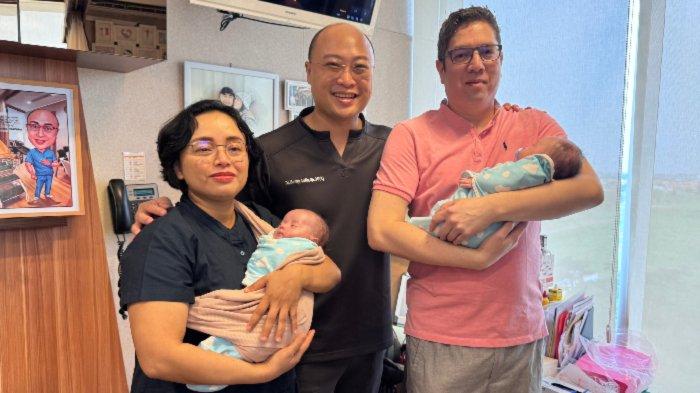 KEMBAR IDENTIK - Nur Endah Wahyuningsih (46), dr Benny, dan Jordy Bertrand (44) di Morula IVF Surabaya, Kamis (19/6/2025). Pasangan suami istri ini tengah menggendong si kembar Alysha dan Elmyra, buah penantian panjang dari program kehamilan. Istimewanya, bayi kembar identik tersebut lahir dari satu embrio pada program kelima IVF yang dilakukan Nur Endah di usianya 45 tahun, sehingga disebut sangat langka