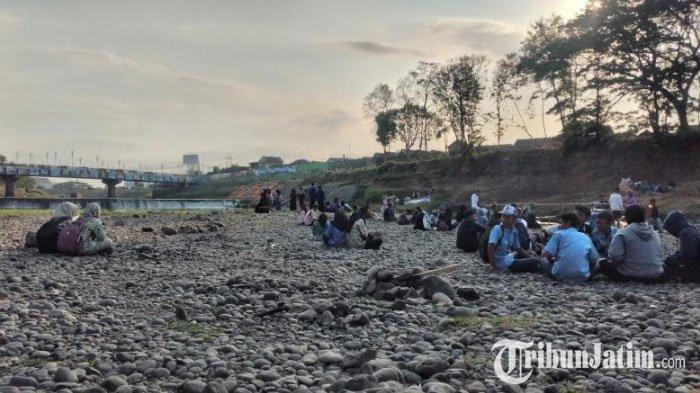 Para muda mudi nikmati senja sambil duduk di atas permukaan sungai di Madiun yang mengering selama musim kemarau Rabu (20/9/2023).