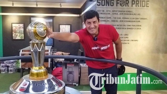 PIALA - Pelatih Madura United, Alfredo Vera menyentuh replika Piala Liga 2 Persebaya yang dipajang di Kantor Marketing Persebaya, Sutos, Surabaya, Sabtu (19/4/2025). Alfredo Vera, menjadi sosok penting di balik keberhasilan Madura United terhindar dari degradasi, dan tetap bertahan di Liga 1 musim depan.
