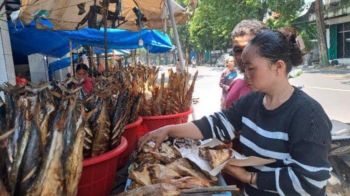 Ikan Asap - Chusnul saat melayani pembeli ikan asap yang dijualnya, di jalur Pantura Tuban yang terletak di Kelurahan Karangsari, Kecamatan/Kabupaten Tuban.Selasa (8/4/2025). Berkah libur Lebaran Chusnul raup omzet jutaan rupiah per harinya.