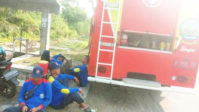 Para personel Damkar Bangkalan melepas lelah dengan berteduh dari sengatan terik karena panasnya matahari di kawasan jalur tanjakan Gunung Gigir, Kecamatan Blega dalam kegiatan water blasting untuk membersihkan kerak-kerak bekas air garam bercampur oli dan solar yang melekat di aspal sebagai pemicu terjadinya kecelakaan, Kamis (21/9/2023).