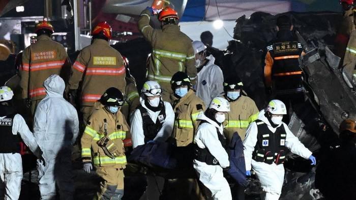 Petugas pemadam kebakaran dan petugas penyelamat membawa jenazah korban di dekat lokasi kejadian pesawat seri Boeing 737-800 Jeju Air jatuh dan terbakar di Bandara Internasional Muan di Provinsi Jeolla Selatan, sekitar 288 kilometer barat daya Seoul pada 29 Desember 2024. - Sebuah pesawat Jeju Air yang membawa 181 orang dari Thailand ke Korea Selatan jatuh pada saat kedatangan, menabrak penghalang dan terbakar, menyebabkan semua orang kecuali dua orang dikhawatirkan tewas.