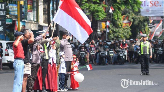 Anggota polisi dari Polresta Malang Kota, TNI, pelajar, warga, serta pengguna jalan memberikan hormat kepada bendera Merah Putih dan menyanyikan lagu Indonesia Raya saat peringatan detik-detik proklamasi di simpang empat Jalan Raya Ijen, Kota Malang, Jawa Timur, Sabtu (17/8/2024)
