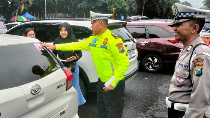 IMBAUAN MUDIK - Personel Satlantas Polres Bondowoso saat memasang stiker bertajuk “Mudik Aman, Keluarga Nyaman” serta informasi “Hotline Mudik Polri 110” di kendaraan warga, pada Minggu (16/3/2025). Tak hanya pemasangan stiker, polisi juga gencar mensosialisasikan untuk selalu berhati-hati selama perjalanan mudik. 