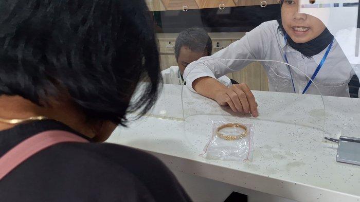 Seorang ibu tengah menggadaikan gelang emas demi kebutuhan jahit seragam anak sekolah jelang Tahun Ajaran Baru, Kantor Pegadaian Cabang Ngawi, Selasa (9/7/2024)