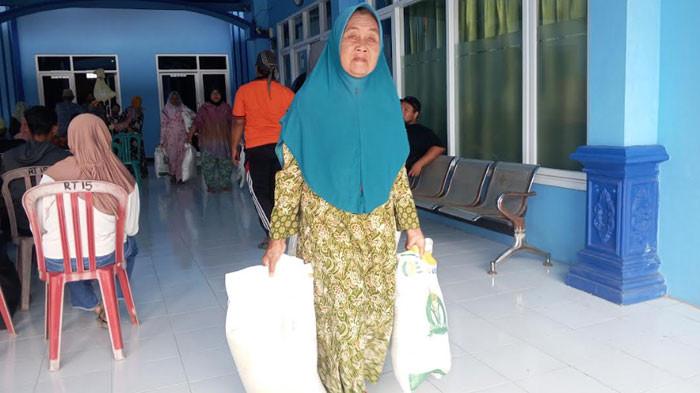 BANTUAN PANGAN - Seorang warga Desa Srikaton, Kecamatan Ngantru, Kabupaten Tulungagung, Jawa Timur membawa dua karung beras bantuan pangan, seberat 20 kg untuk 2 bulan, Sabtu (26/7/2025). Bulog Cabang Tulungagung menemukan beras bantuan pangan diperjualbelikan di media sosial.