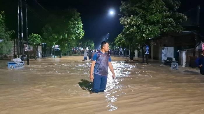 Seorang warga tengah berjalan melintasi banjir yang menggenangi Jalan Alternatif, dari arah Kota Madiun ke Caruban, Kabupaten Madiun,masuk Desa Ngadirejo, Kecamatan Wonoasri, Kabupaten Madiun, Kamis malam (5/12/2024).