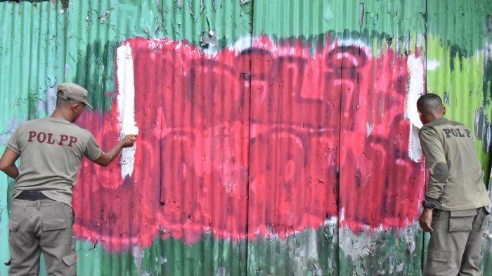 TERTIBKAN VANDALISME - Petugas Satpol PP Surabaya menertibkan sejumlah coretan bertuliskan 