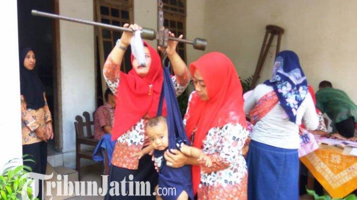 Kader Posyandu tengah menimbang balita, sebagai bagian pemantauan tumbuh kembang anak.