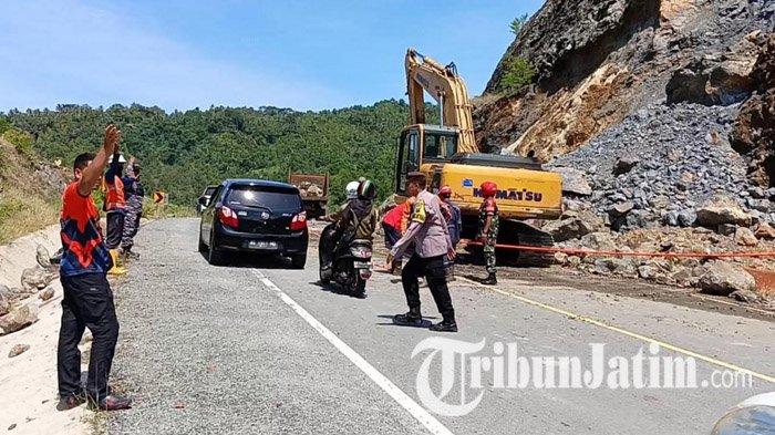 MEMINDAHKAN BEBATUAN - Sebuah ekskavator tengah bekerja memindahkan bebatuan, material longsor dari bukit yang menutup Jalur Lintas Selatan (JLS) Tulungagung-Trenggalek di Dusun Soireng, Desa Keboireng, Kecamatan Besuki, Kabupaten Tulungagung, Jawa Timur, Minggu (13/4/2025) siang. Sebelumnya bukit batu di samping JLS runtuh dan menutup jalur sepanjang sekitar 10 meter dengan bebatuan ukuran besar.