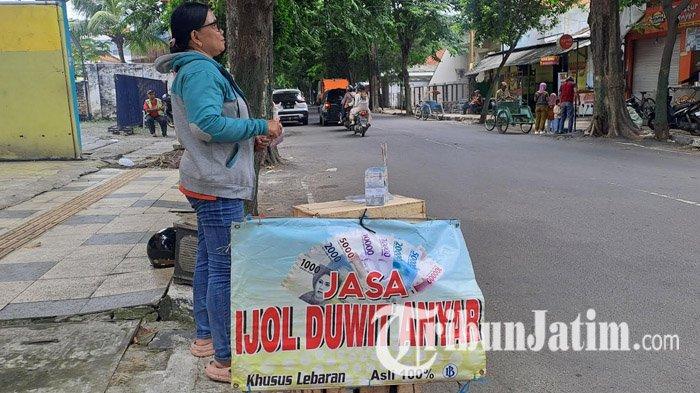  PENUKARAN UANG BARU - Lina, penyedia jasa tukar uang baru di Jalan Basuki Rahmad, Tuban, sedang menunggu penukar uang, Sabtu (22/3/2025). Dia mengatakan, tahun 2025 ini lebih sepi dibanding tahun lalu. (Tribun Jatim Network/Muhammad Nurkholis)

