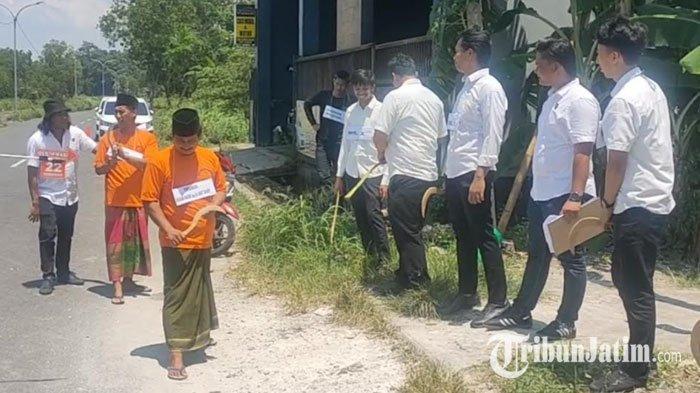 Tersangka kakak beradik berseragam tahanan, Hasan Basri (depan) dan Wardi tiba di lokasi kejadian sambil menggenggam celurit di lokasi rekonstruksi, jalur kembar Ringroad Kota Bangkalan, Senin (26/2/2024).  Empat korban diperankan para personel Satreskrim Polres Bangkalan yang dalam posisi berdiri mengenakan seragam putih