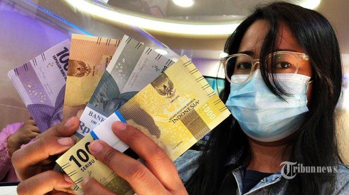 TUKAR UANG BARU - Seorang wanita menunjukan pecahan uang baru. Adapun layanan penukaran uang baru untuk Ramadan dan Idul Fitri 2025 digelar mulai 3-27 Maret 2025.