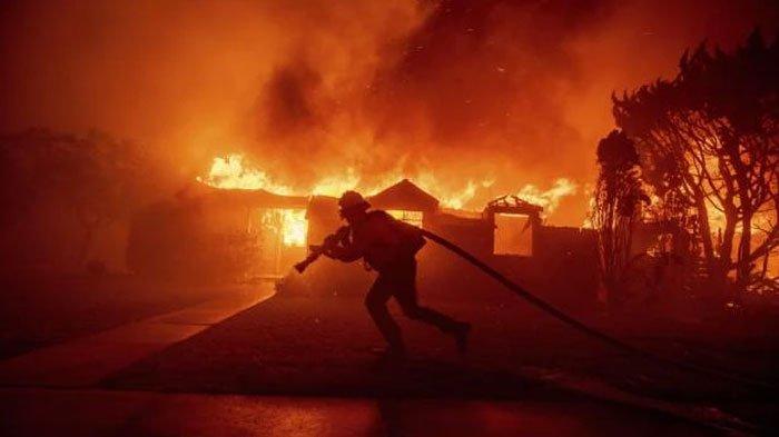 Seorang petugas pemadam kebakaran berjuang melawan api yang membakar sebuah bangunan di kawasan Pacific Palisades, Los Angeles, California, Amerika Serikat, Selasa, 7 Januari 2025.